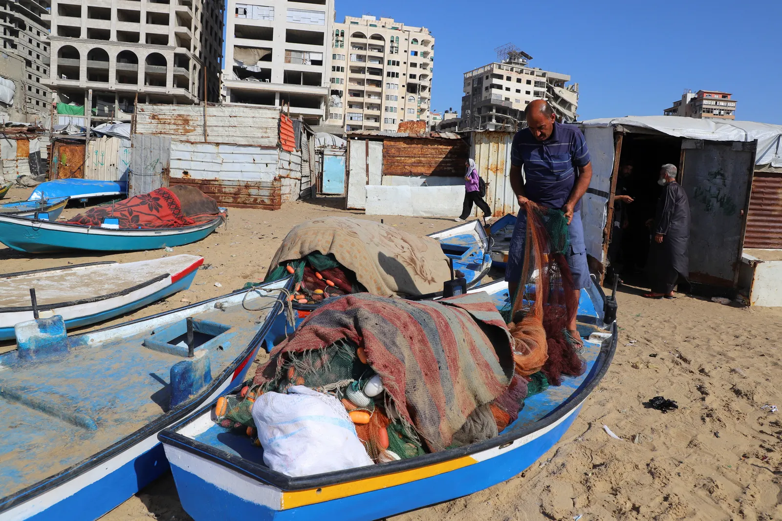 Gazan fishermen patch up dinghies with door frames to keep afloat